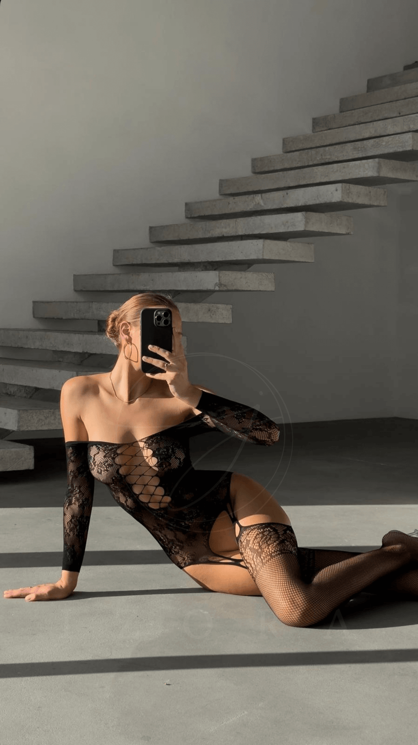Woman modeling Laura vücut çorabı with elegant lace design, showcasing comfort and style in a modern setting.